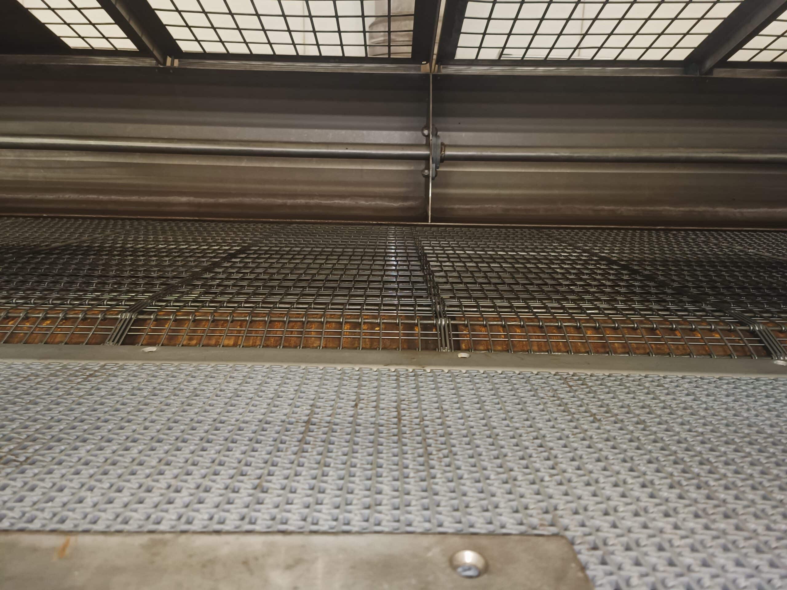 Vue en contre-plongée de caillebotis et grilles métalliques industrielles superposées avec une maille fine au premier plan.